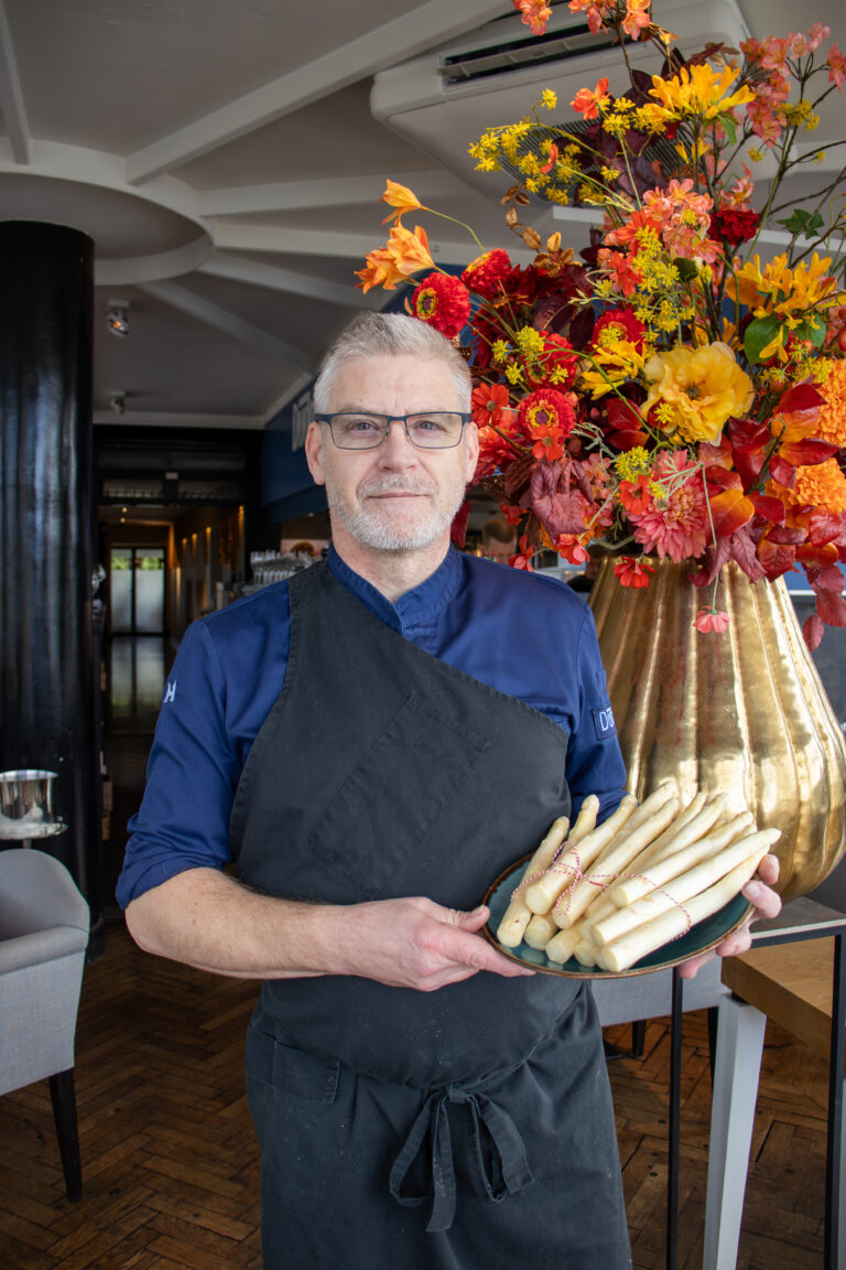 JJ met asperges op een bord en bloemen achter zich